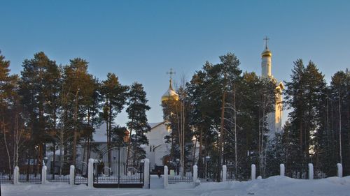 Panoramic view of trees and building against sky during winter