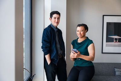 Portrait of confident male and female colleagues against wall at office