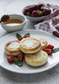 Cottage cheese pancakes, ricotta fritters on ceramic plate with fresh strawberry. 