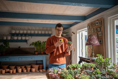 Young man choosing plant in store by making photo, reading information in mobile application