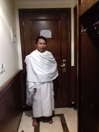 Portrait of young man standing against door at home