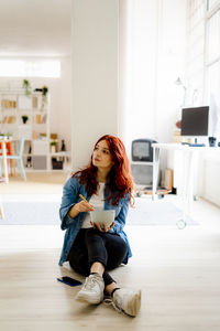 Full length portrait of woman sitting in corridor