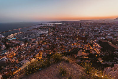 High angle view of city lit up at sunset