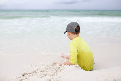 Rear view of boy sitting at beach