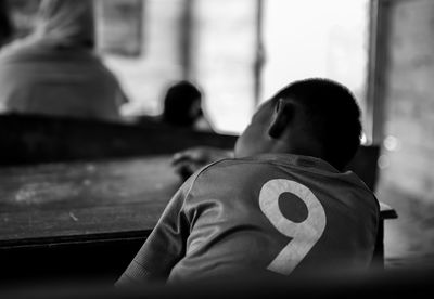 Rear view of boy relaxing on table in room