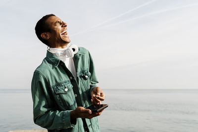 Young man looking at sea shore against sky