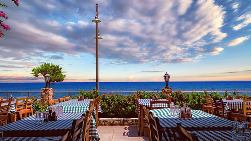 Chairs and tables at beach against sky