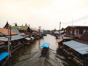 Houses by river amidst buildings against sky