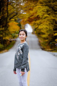 Portrait of cute girl standing on road during autumn