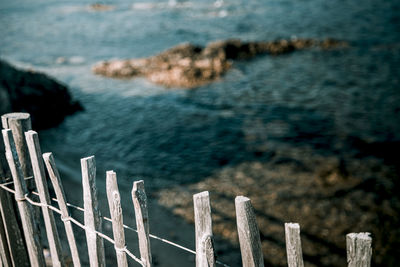 Wooden post on fence by sea