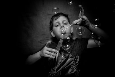 Close-up of boy blowing bubbles against wall