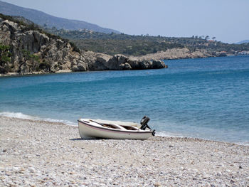 Boat moored on shore by sea against sky