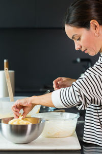 Woman putting apples while cooking apple pie in the modern kitchen