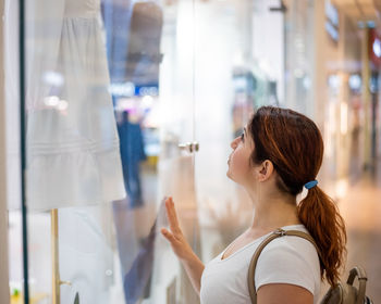 Portrait of young woman looking away at store