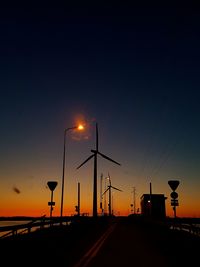Street lights on road against sky during sunset