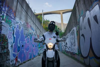 Man standing by graffiti on wall