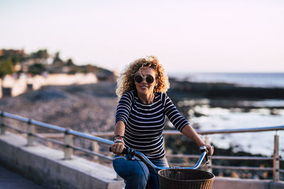Full length of senior woman standing by railing against sea