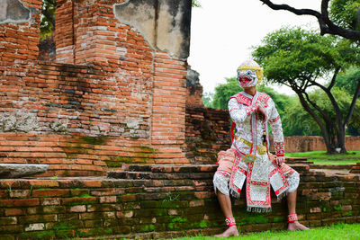 Full length of man standing against brick wall