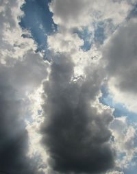 Low angle view of sunlight streaming through clouds