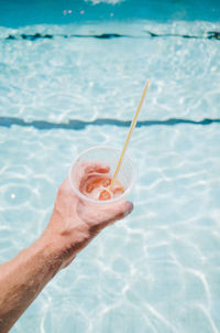 Close-up of hand holding drink at swimming pool