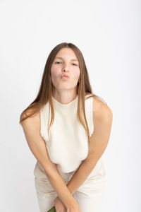 Portrait of young woman standing against white background