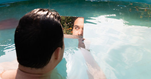 Rear view of couple swimming in pool