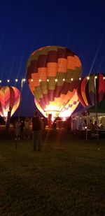 Multi colored balloons on field against clear sky at night