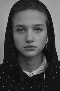 Close-up portrait of young woman wearing headphones wearing hood