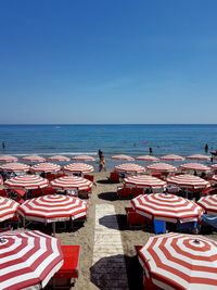 Chairs on beach against clear blue sky