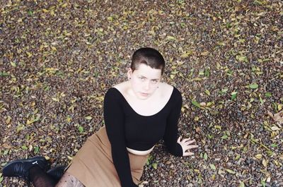 High angle portrait of young woman sitting on field