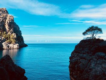 Rock formation by sea against blue sky