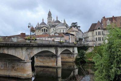 Arch bridge over river against perigueux cathedral