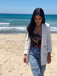 Young woman standing on beach against sea