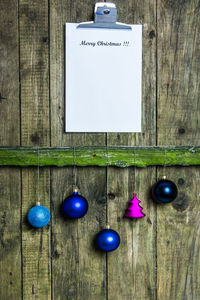 Christmas ornaments with clipboard hanging on wooden fence