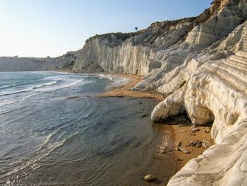 Scenic view of cliff by sea against clear sky