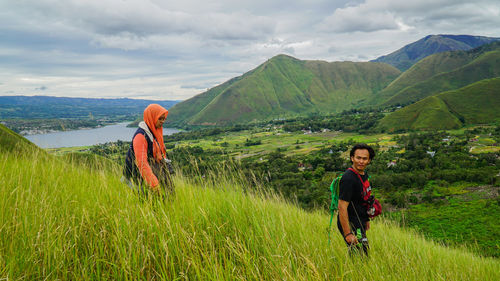 Siblings standing on mountain against sky