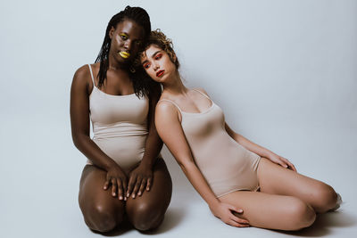 Young women sitting against gray background