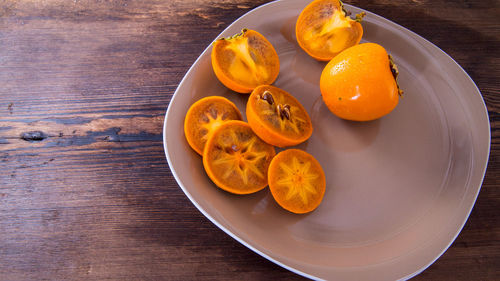 Persimmon cut into halves on a plate on a wooden table,copy space,closeup