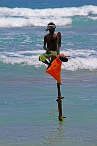 Full length of shirtless man standing in sea