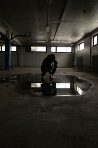 Man touching reflection in puddle at basement