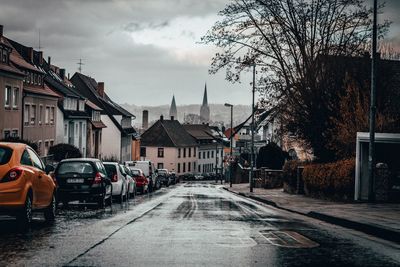 Road amidst buildings in city during rainy season