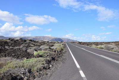 Road leading towards mountain against sky