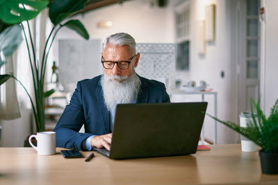 Portrait of senior man using laptop at table