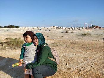 Mother and daughter on land against sky