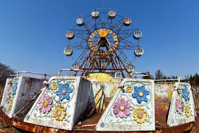 Low angle view of ferris wheel against clear blue sky