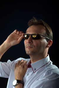 Portrait of man wearing sunglasses against black background