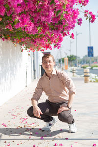 Young man sitting on pink flowering plant