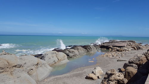 Rocks on beach against blue sky