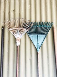 Close-up of rakes against corrugated iron