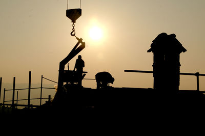Silhouette people standing against orange sky